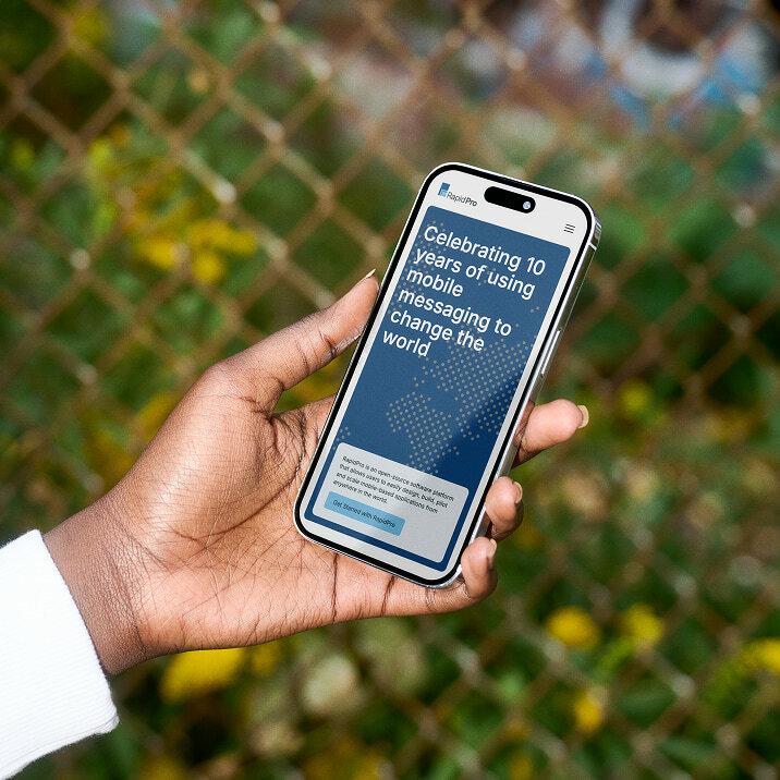 Hand holding a phone showing a RapidPro website mockup.