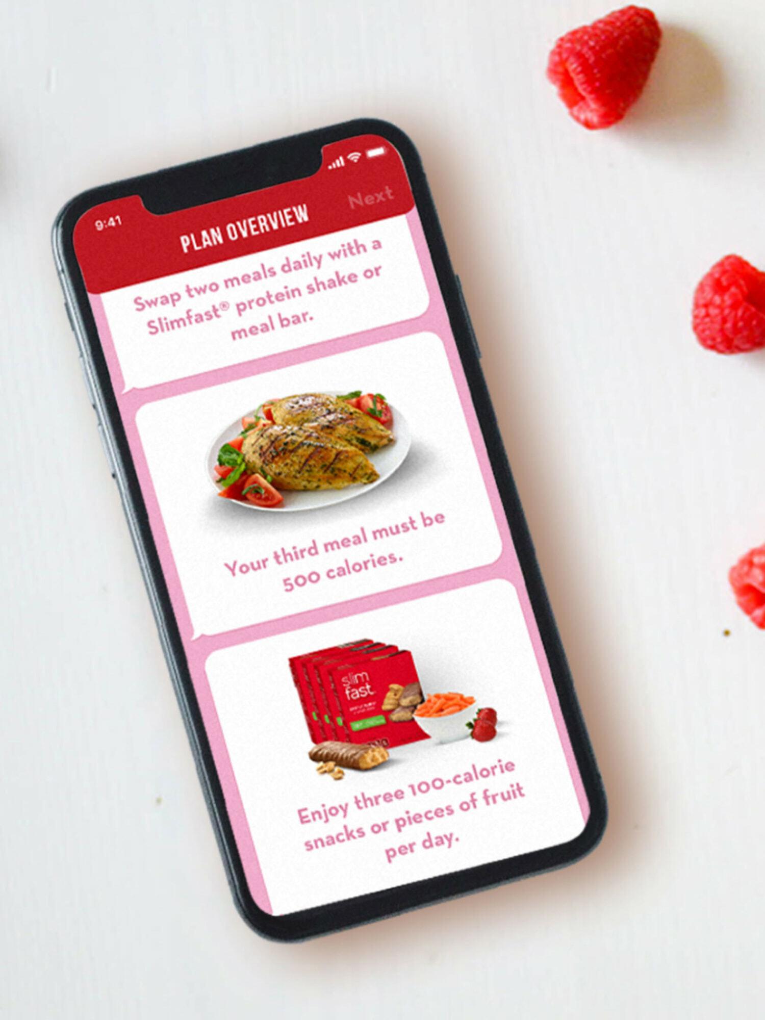 Smartphone showing a meal plan overview app beside fresh raspberries