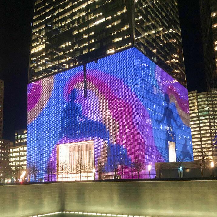 City building facade lit with blue, purple, and pink digital patterns at night