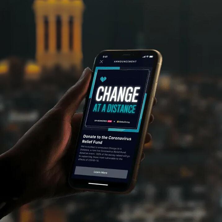 Hand holding a phone showing a Change at a Distance relief fund announcement