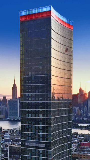 Tall glass skyscraper with red and blue lights along the roofline