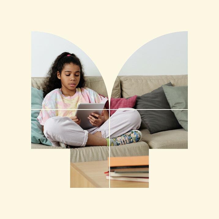 Child sitting on a couch using a tablet inside a butterfly-shaped frame