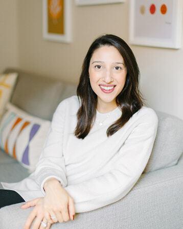 Smiling woman seated on a couch in a softly decorated office