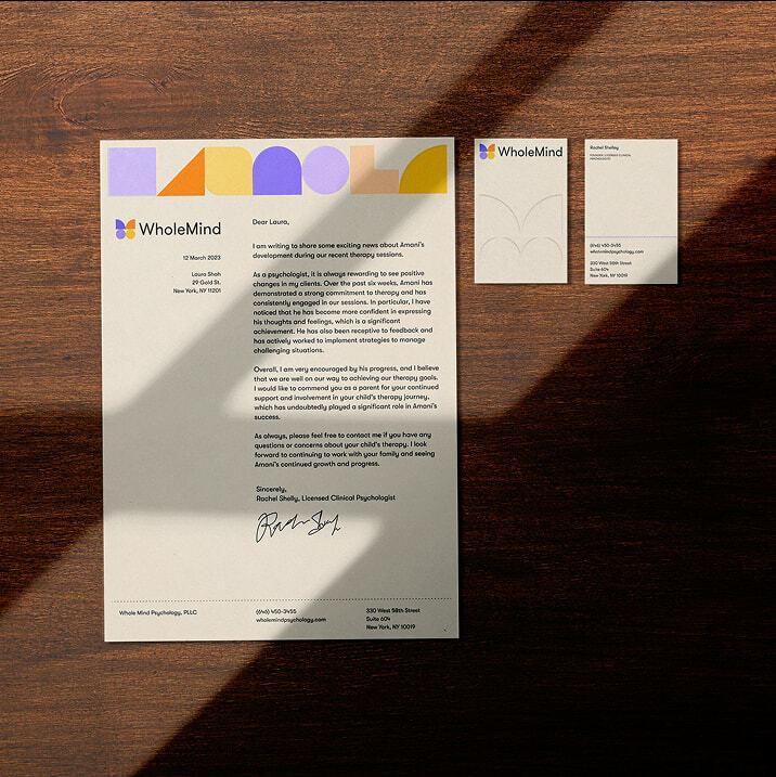 WholeMind letterhead and business cards arranged on a wooden table in sunlight