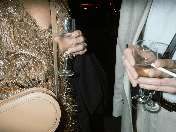 Two dressed-up people holding champagne glasses at night