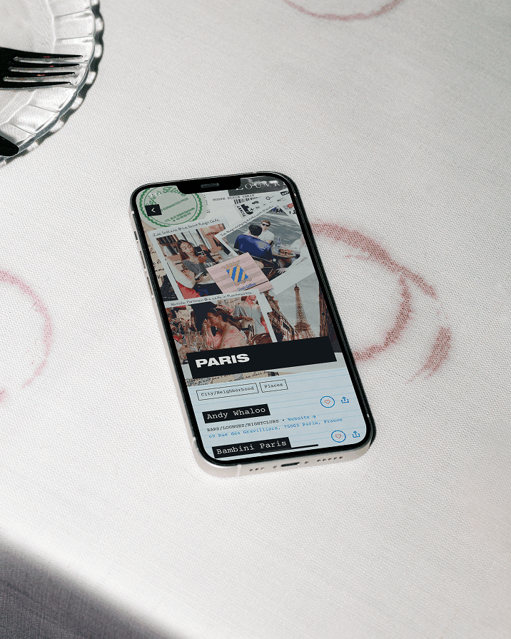 Phone on a table showing a Paris guide page in an app