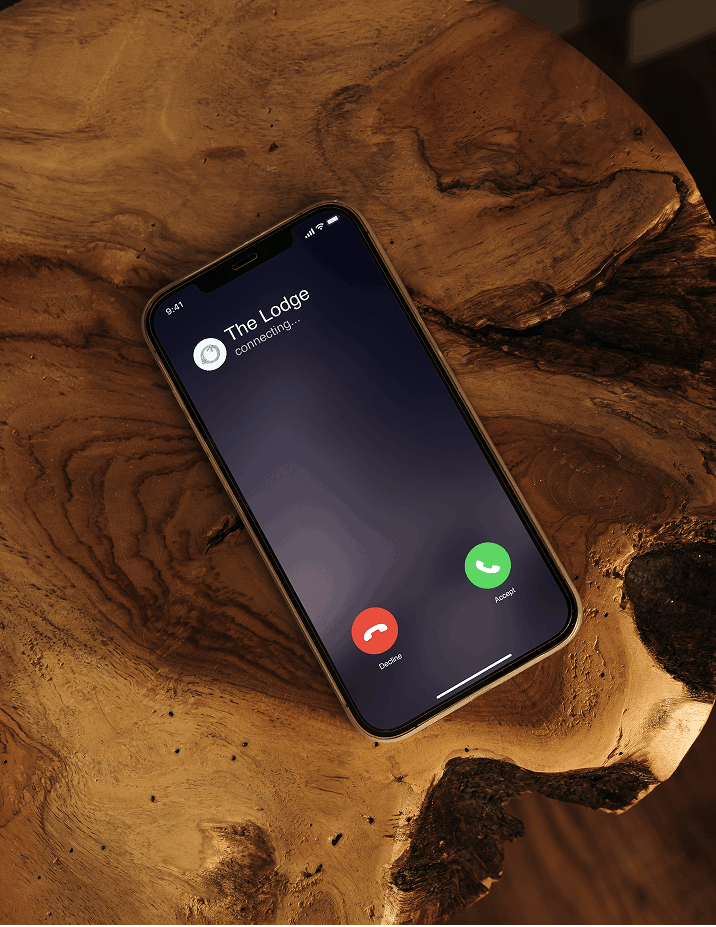 Smartphone showing The Lodge incoming call on a wood table