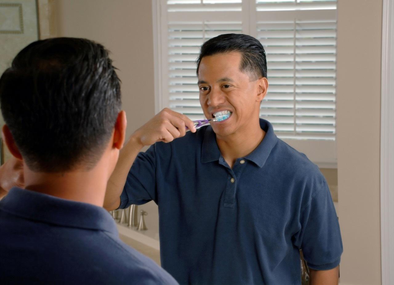 Man brushing his teeth while looking in a bathroom mirror