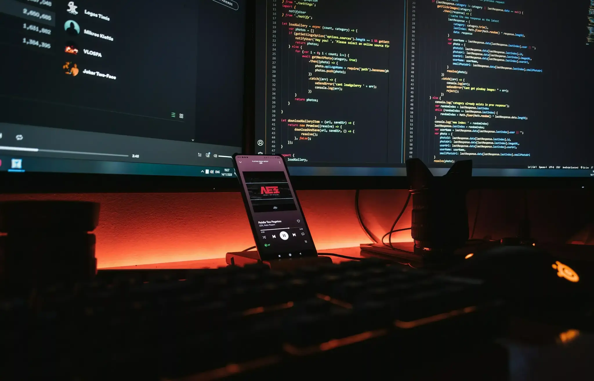Coding workstation with multiple monitors, phone, keyboard, and red backlighting