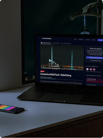 Laptop showing online charity campaign on a desk at night with a smartphone nearby