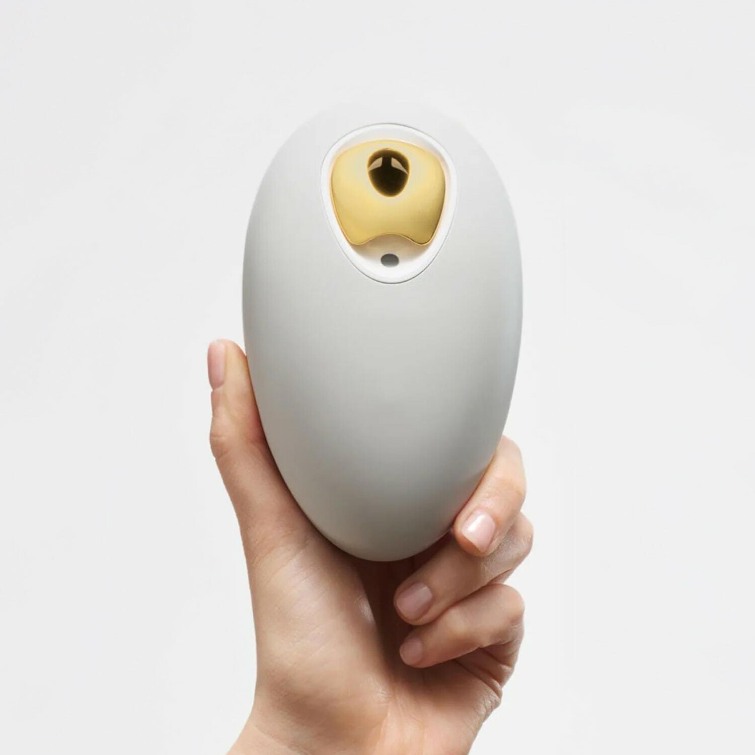 Hand holding a small oval white and gold device