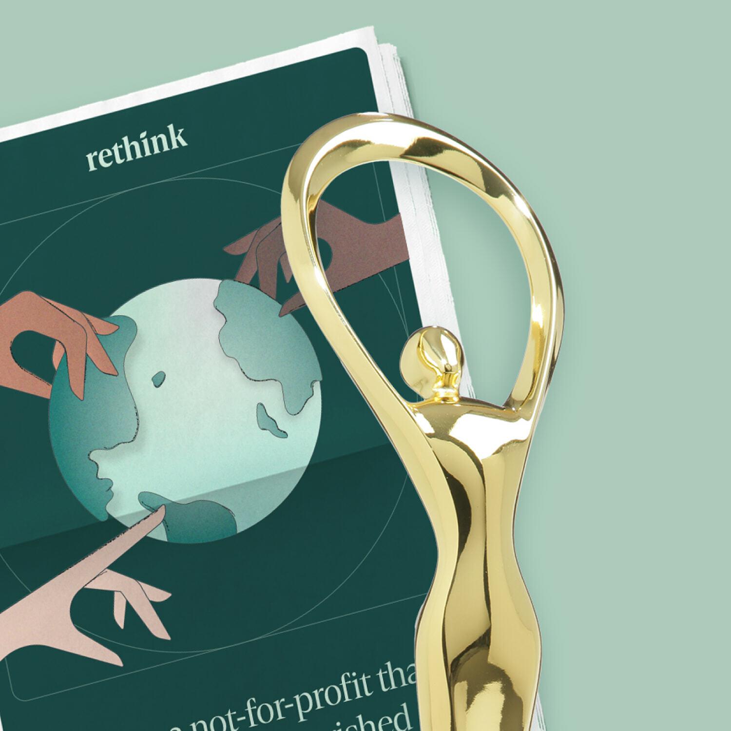 Gold abstract trophy beside a Rethink booklet