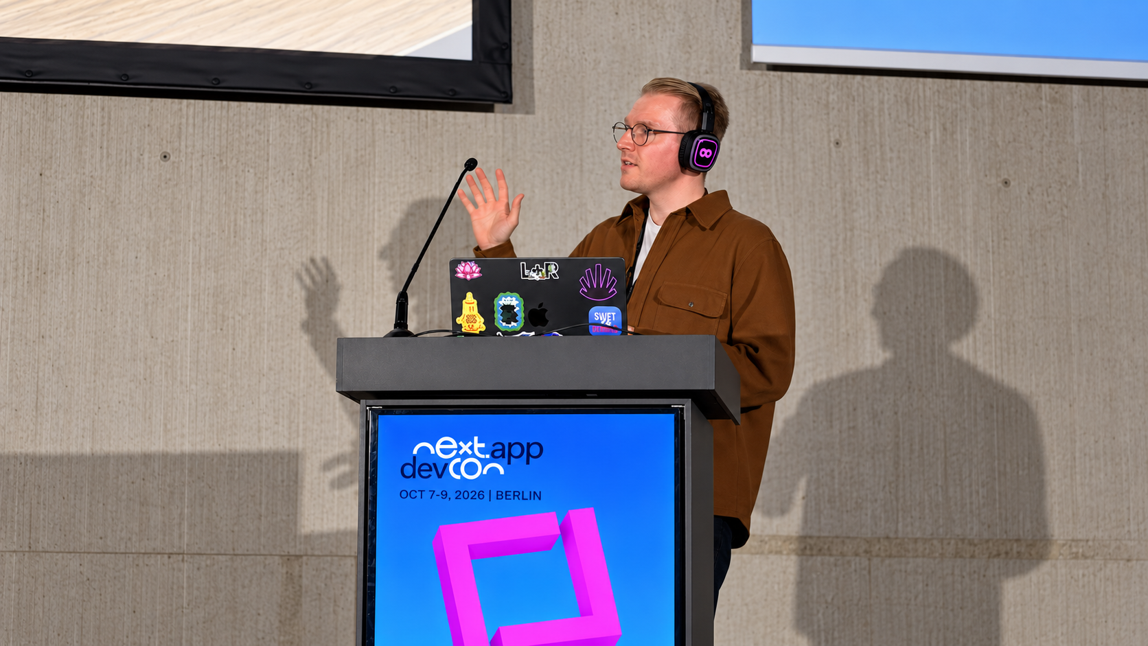 Kelvin Harron presenting at the next.app devCon 2026 podium in Berlin.