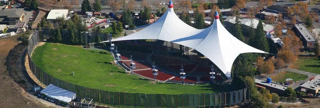 Aerial view of an outdoor amphitheater with two white canopy roofs
