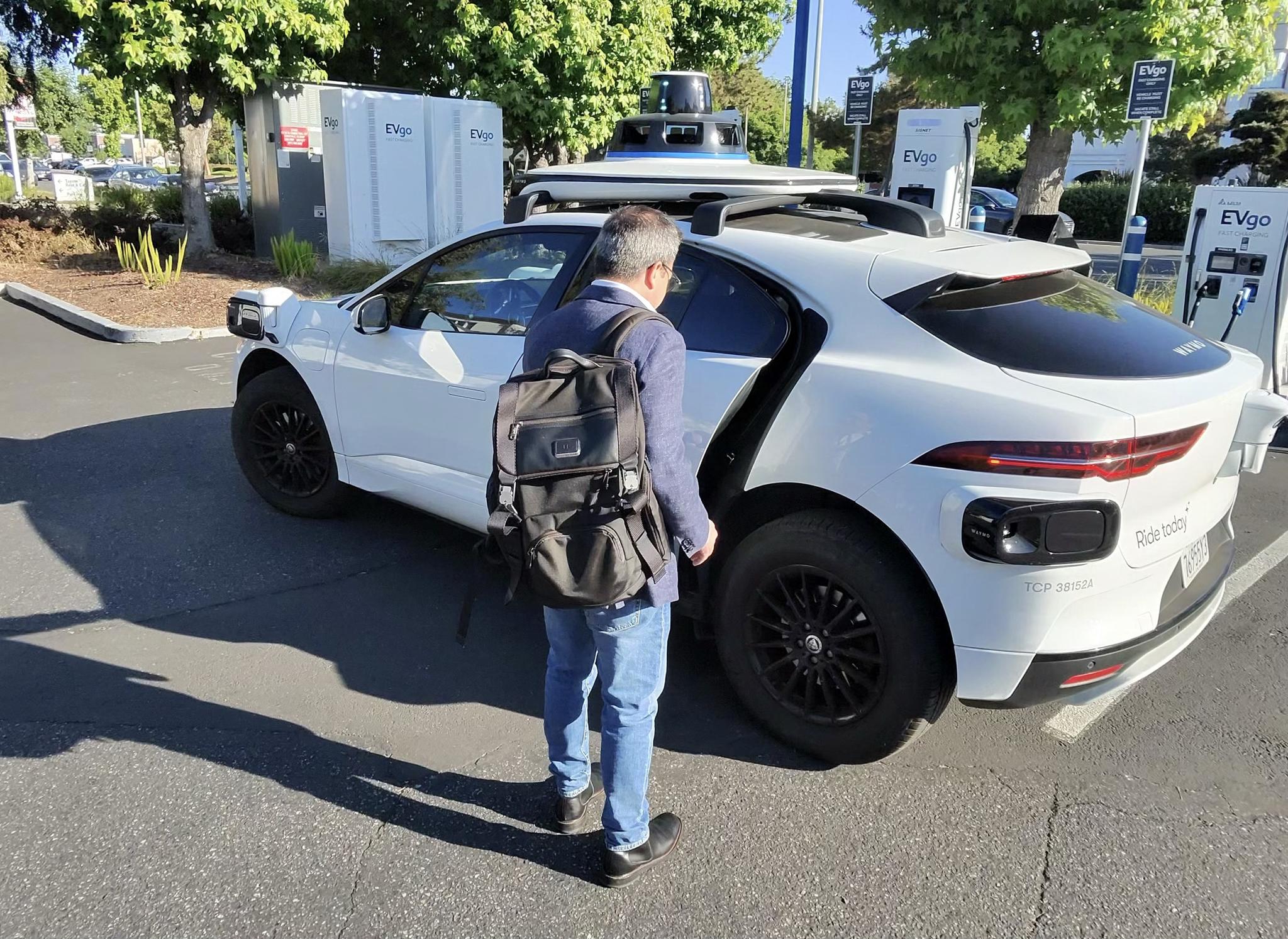 Person charging a white electric car at a public charging station