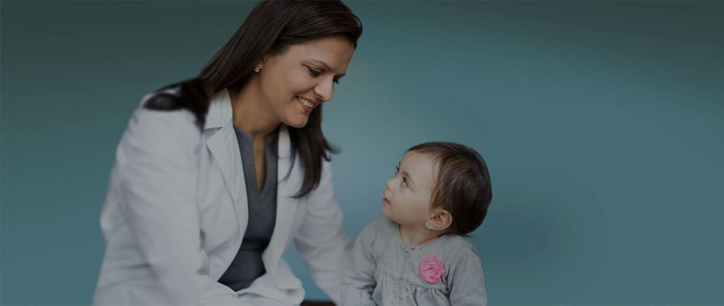 Doctor and young child seated together against a teal background