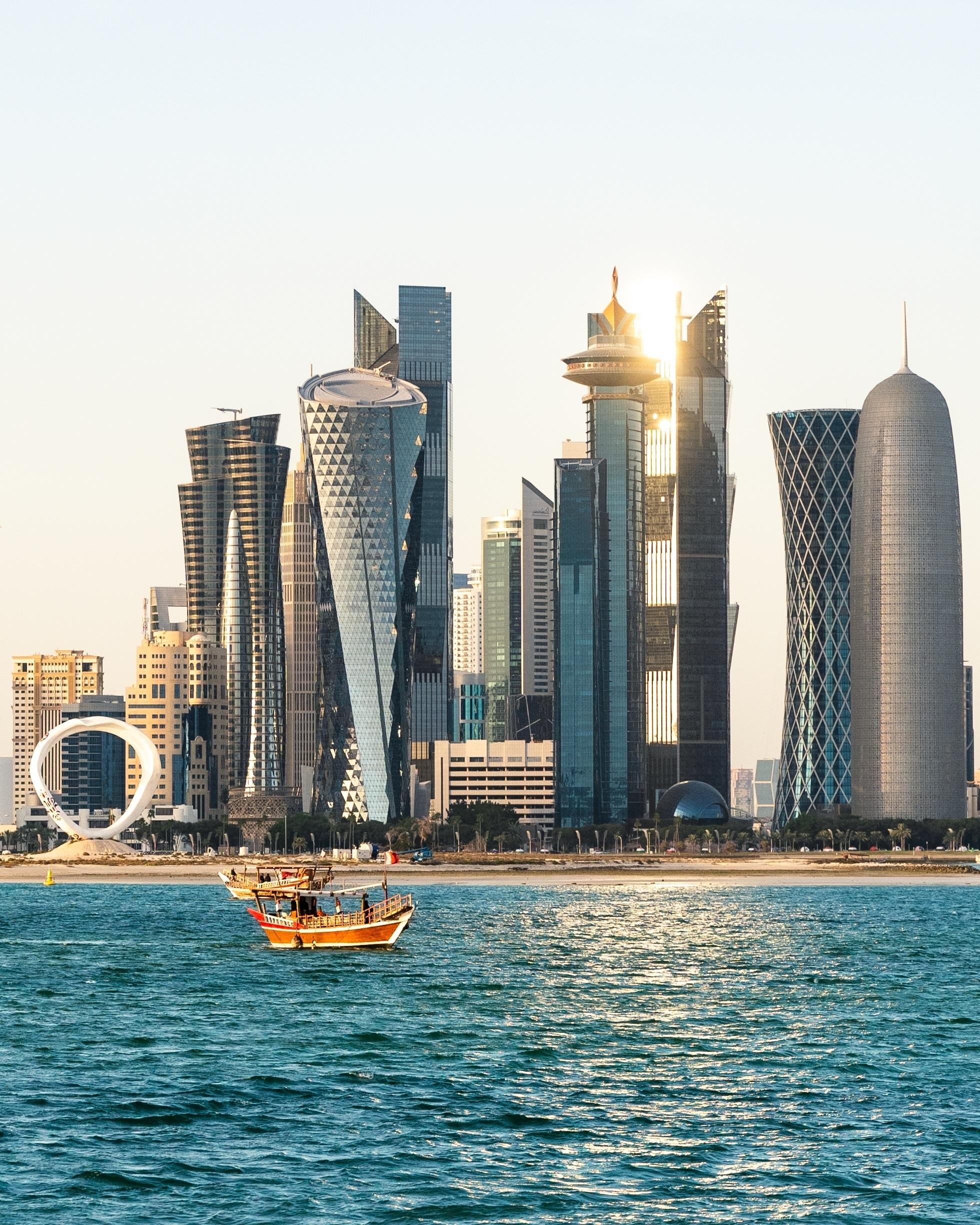 Doha skyline at sunset with a small boat on the water